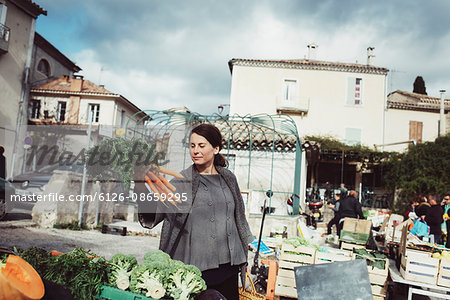 France, Languedoc-Roussillon, Sauve, Young tourist looking at carrot on market