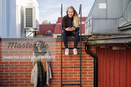 Sweden, Vasterbotten, Umea, Two young women using phones