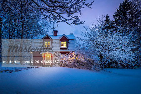 Sweden, Uppland, Varmdo, Wooden house in snow at dusk