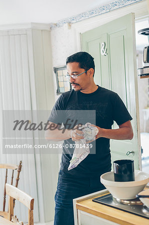 Sweden, Man drying dishes in kitchen