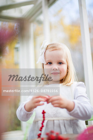 Finland, Girl (2-3) stringing beads in house