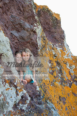 Two young girls looking out of a hole in the rocks