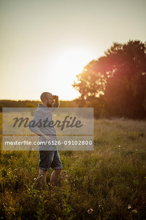 Man standing in grassy field at sunset