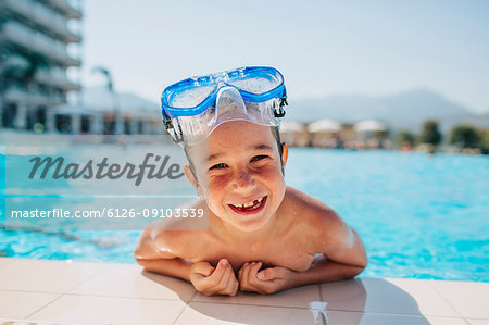 A happy young boy leaning on the edge of a pool