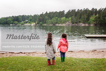 Two girls standing by lake shore