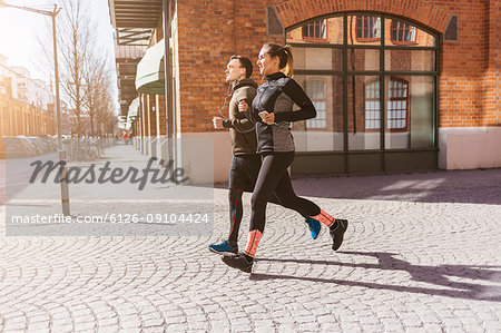 Man and woman running along street in Stockholm, Sweden