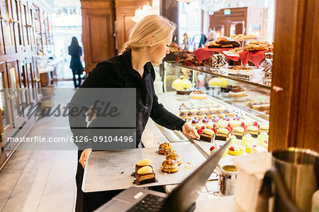 Baker putting baked goods in display window in Sweden