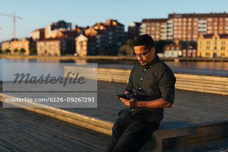 Man sitting on boardwalk using smart phone
