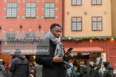 Young man looking at smart phone at market