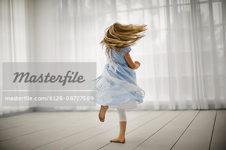Little girl joyfully spinning around in bare feet in an empty room