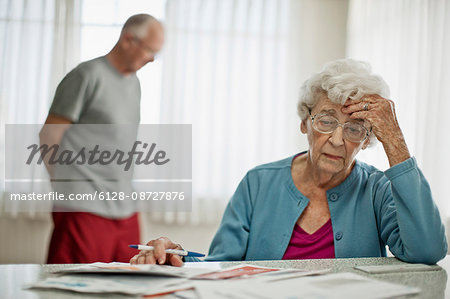 Anxious elderly couple worry about how they will pay all the bills they have received.