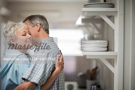Affectionate mature couple tenderly embrace in the kitchen.