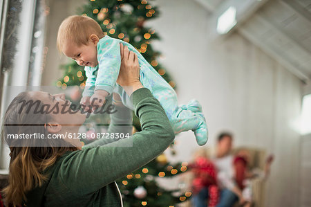 Mother playfully holding up her baby daughter.