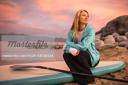 Young woman sitting on her paddleboard.