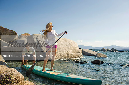 Young man helping to launch his partner's paddleboard.