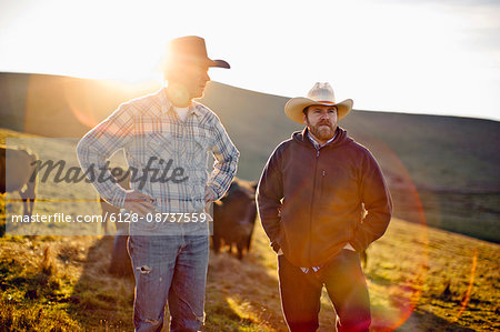 Two farmers standing on a paddock.