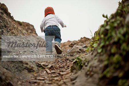 Young boy climbing up a dirt track.