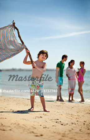 Young boy waves flag at beach.
