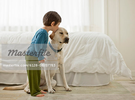 Young boy playing with his dog in a bedroom.