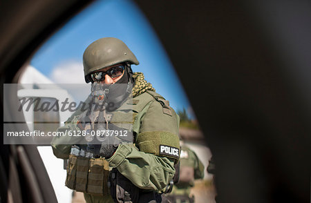 Mid adult army soldier aiming a gun while wearing a protective helmet.