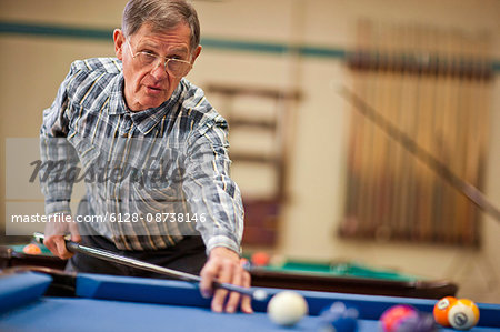 Senior man playing a game of pool.