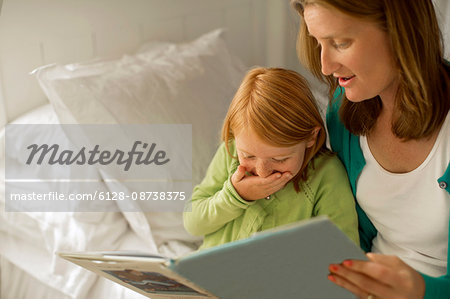 Smiling mother and daughter reading a picture book.