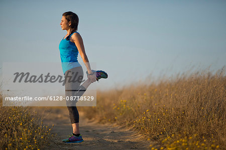 Mid adult woman doing warm up stretches before exercising.