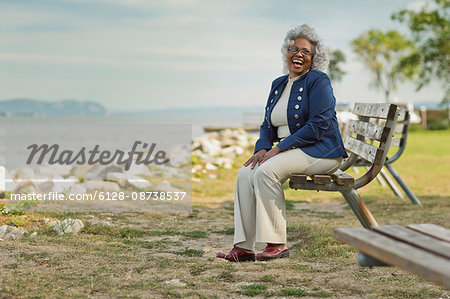 Portrait of a smiling senior woman sitting on a park bench.