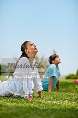Serene mid adult women practicing yoga in a serene green park.
