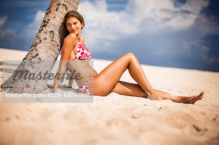 Relaxed young woman sitting on a tropical beach. - Stock Photo