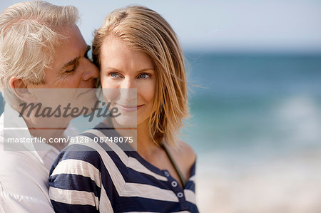 Mid adult woman being affectionate with her husband on the beach.