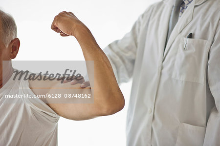 Doctor feeling a patient's flexed bicep muscle.