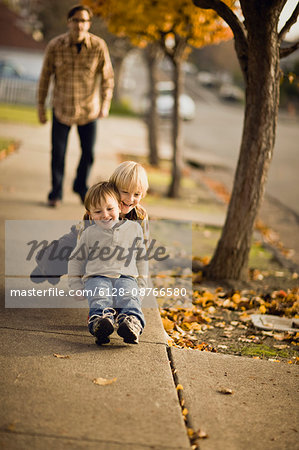 Little boys playing with skateboard.