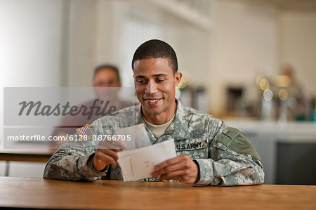 US Army soldier smiles happily as he opens his letters from home.