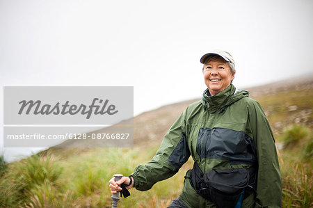 Woman smiles as she stops to admire the scenery on a hike.