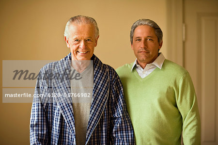 Senior man in his bathrobe and his mature son pose for a portrait.