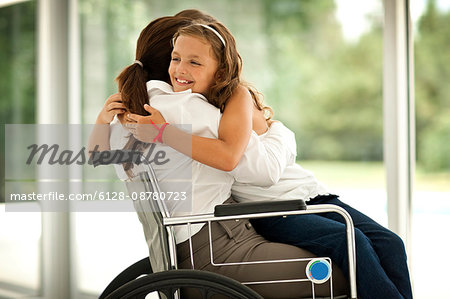 Senior woman in a wheelchair,  receiving a visit from her granddaughter.
