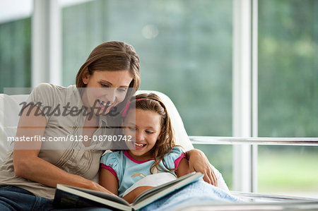 Mother reading young daughter a story in hospital.