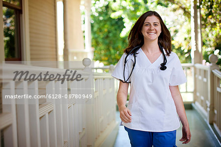 Smiling nurse walking on the porch of rest-home.