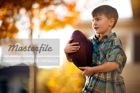 Portrait of boy holding his rugby ball in the backyard.