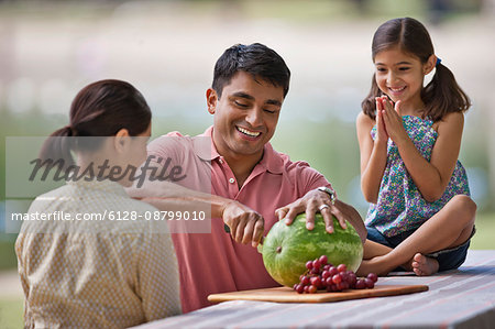 Family enjoying watermelon during a picnic at the park.