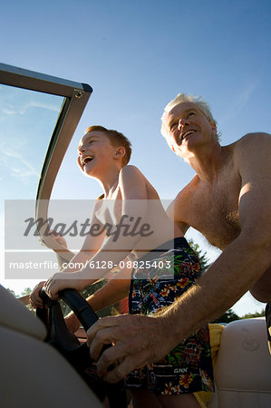 Young boy and his mature grand father driving a boat.