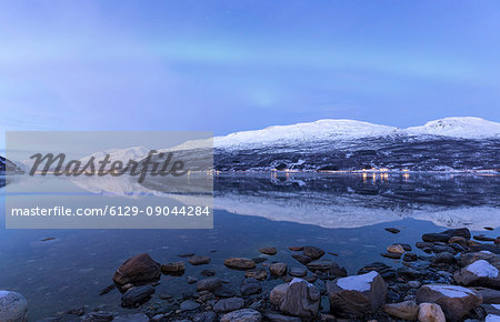 The Northern Lights appear in the sky during twilight. Skarvdalen, Kafjord, Lyngen Alps, Troms, Norway, Lapland, Europe.