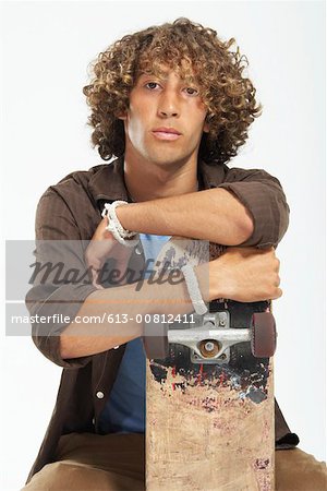 Teenage Boy 16 18 With Curly Hair Leaning On Skateboard