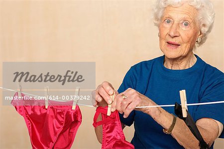 Elderly woman hanging out sexy underwear - Stock Photo