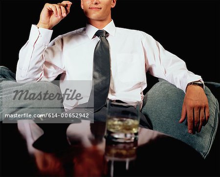 Businessman having a drink and a cigar