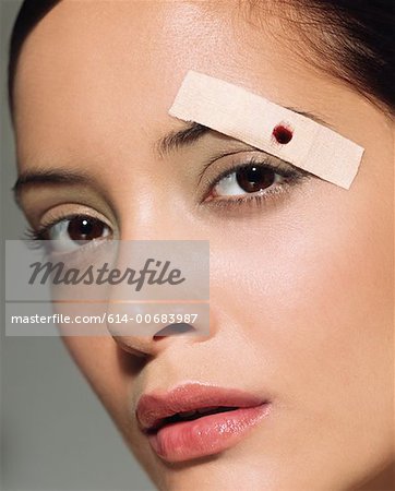 Woman with plaster on her eyebrow