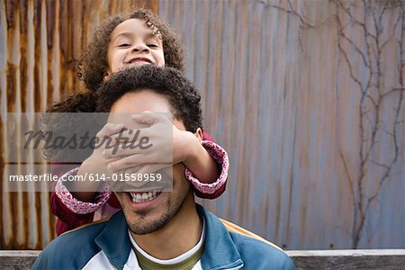 Daughter covering fathers eyes