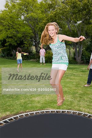 A teenage girl jumping on a trampoline - Stock Photo - Masterfile