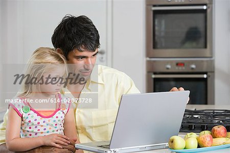 A father and daughter looking at a laptop